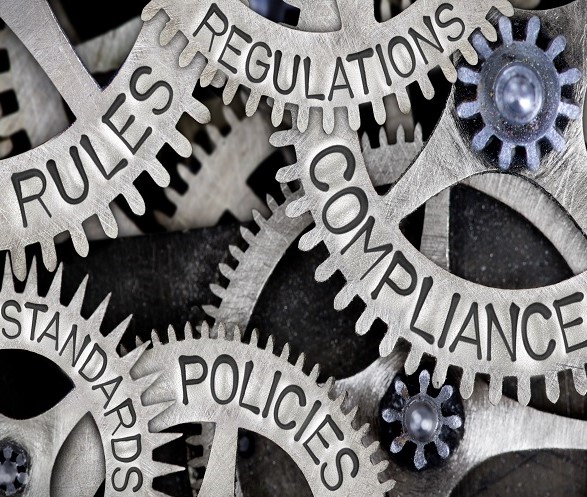 Macro photo of cogs with COMPLIANCE, REGULATIONS, STANDARDS, POLICIES, and RULES words imprinted on the metal surfaces