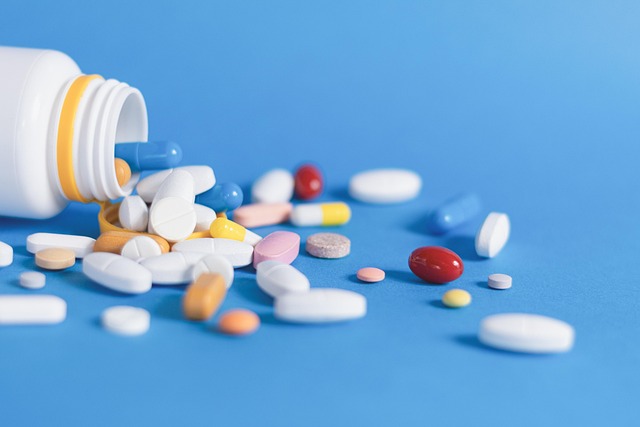 Various pills on a blue background next to a white pill bottle
